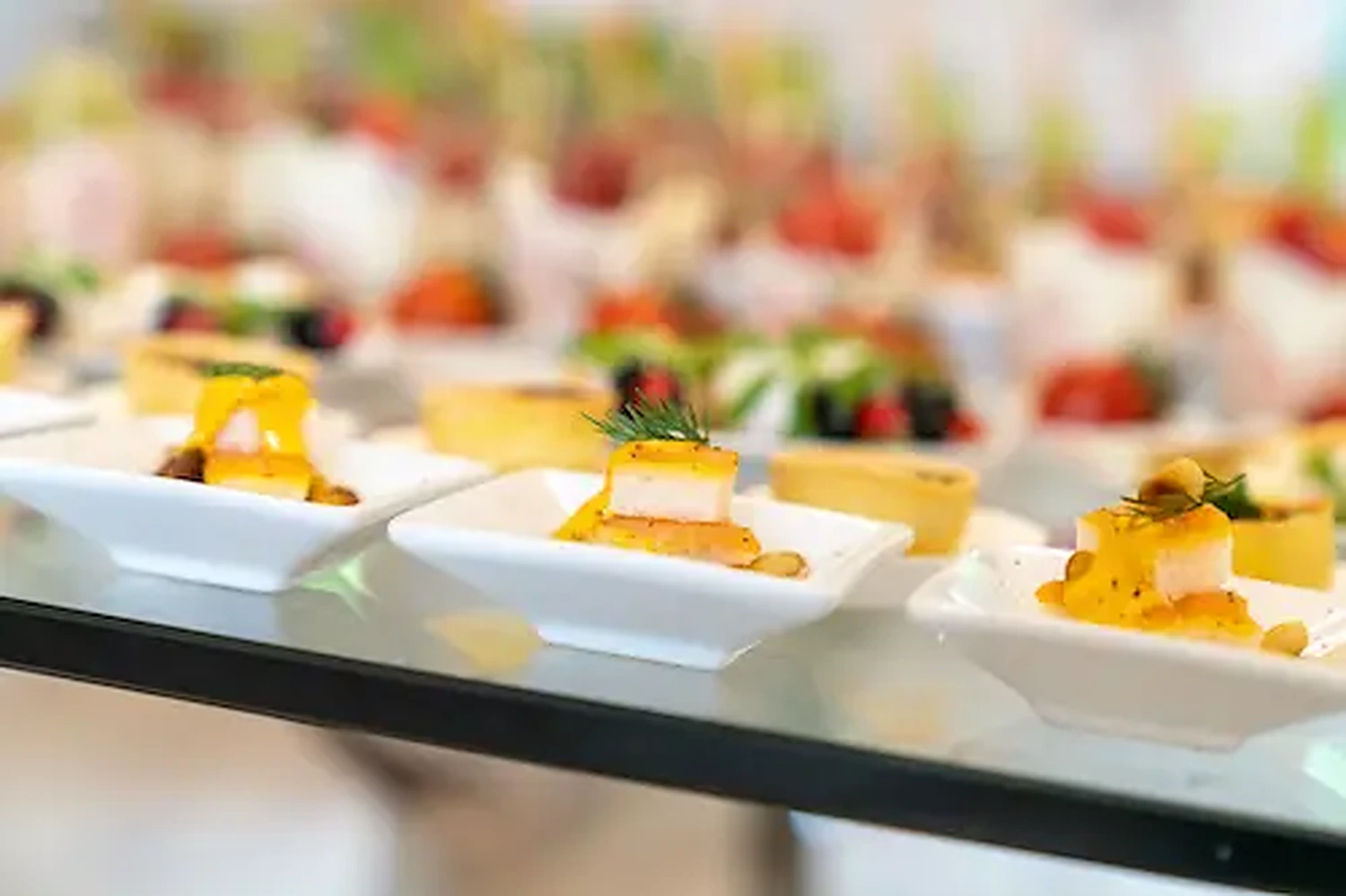 Fingerfood-Arrangement mit geschichteten Mini-Portionen und Kräutern